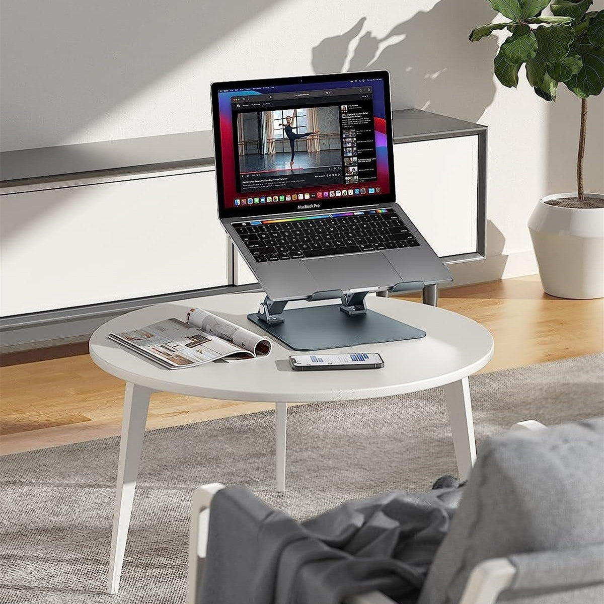 Adjustable aluminum laptop stand with ergonomic design and non slip silicone pads depiction of use on a table