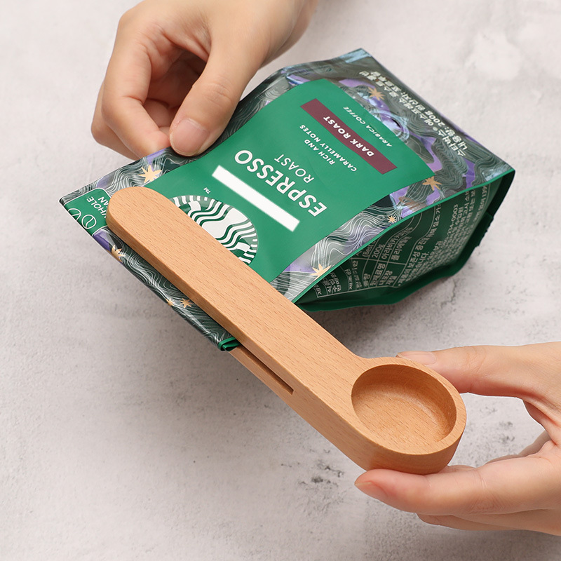 Light colored dual-purpose wooden measuring spoon and sealing clip in use (Color: Light)