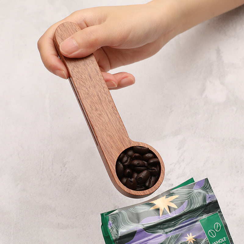 Dual-purpose wooden measuring spoon and sealing clip in use as a spoon