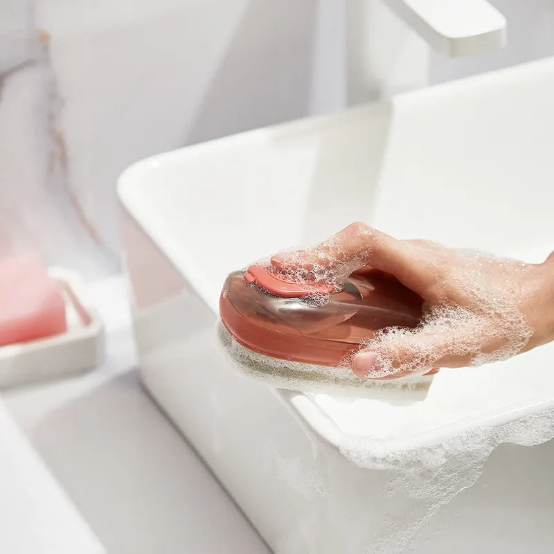 Liquid dispensing shoe cleaning brush with ergonomic grip for washing shoes, clothes, and household items depiction of use on bathroom counter