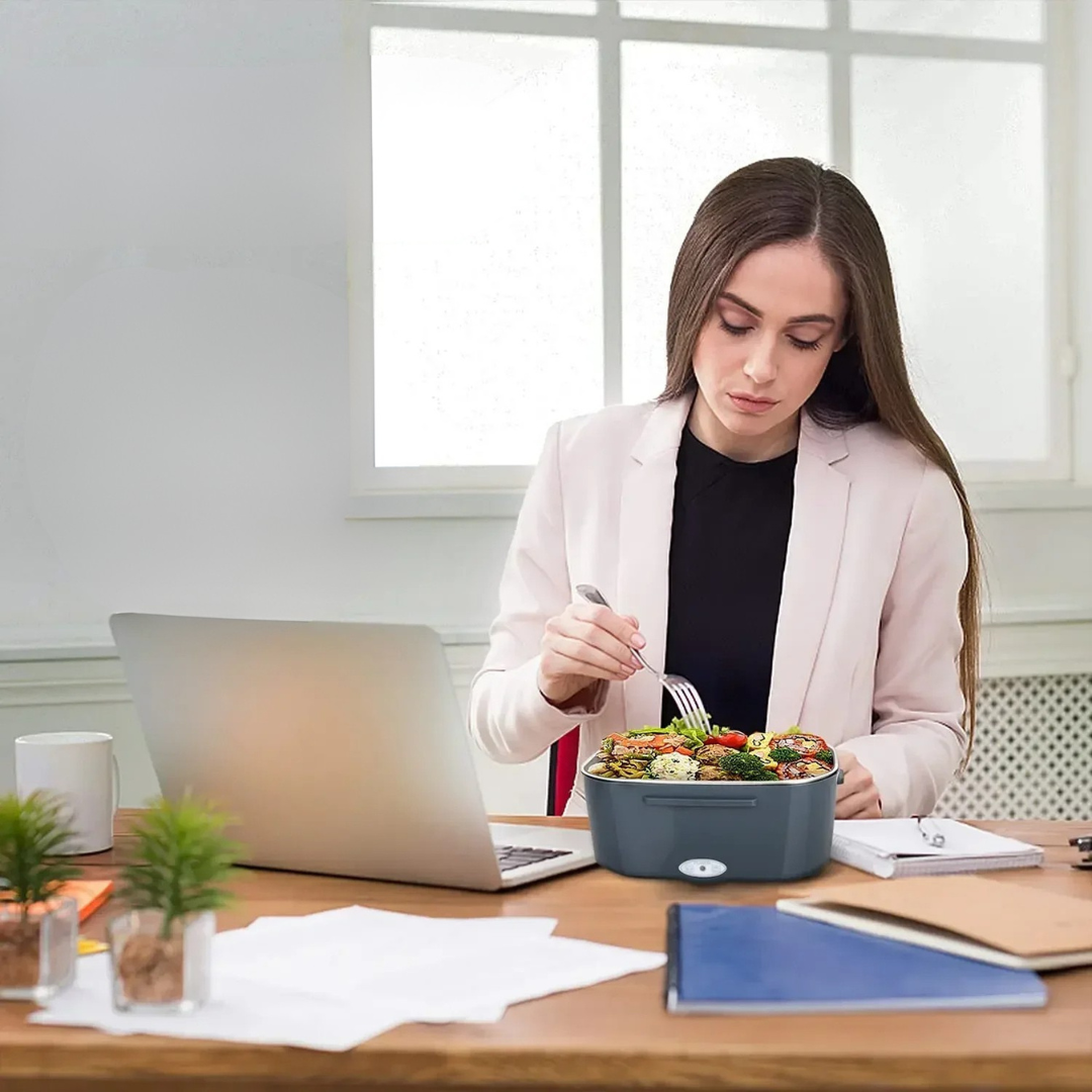 Portable heated lunch box with car and home adapters for warming meals on the go depiction of use at work